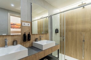 A modern bathroom with two sinks, a large mirror, and a shower enclosure.