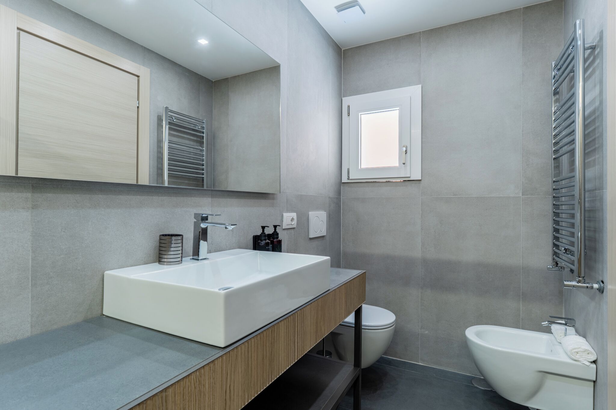 A modern bathroom with a large white sink, a toilet, and a bidet.
