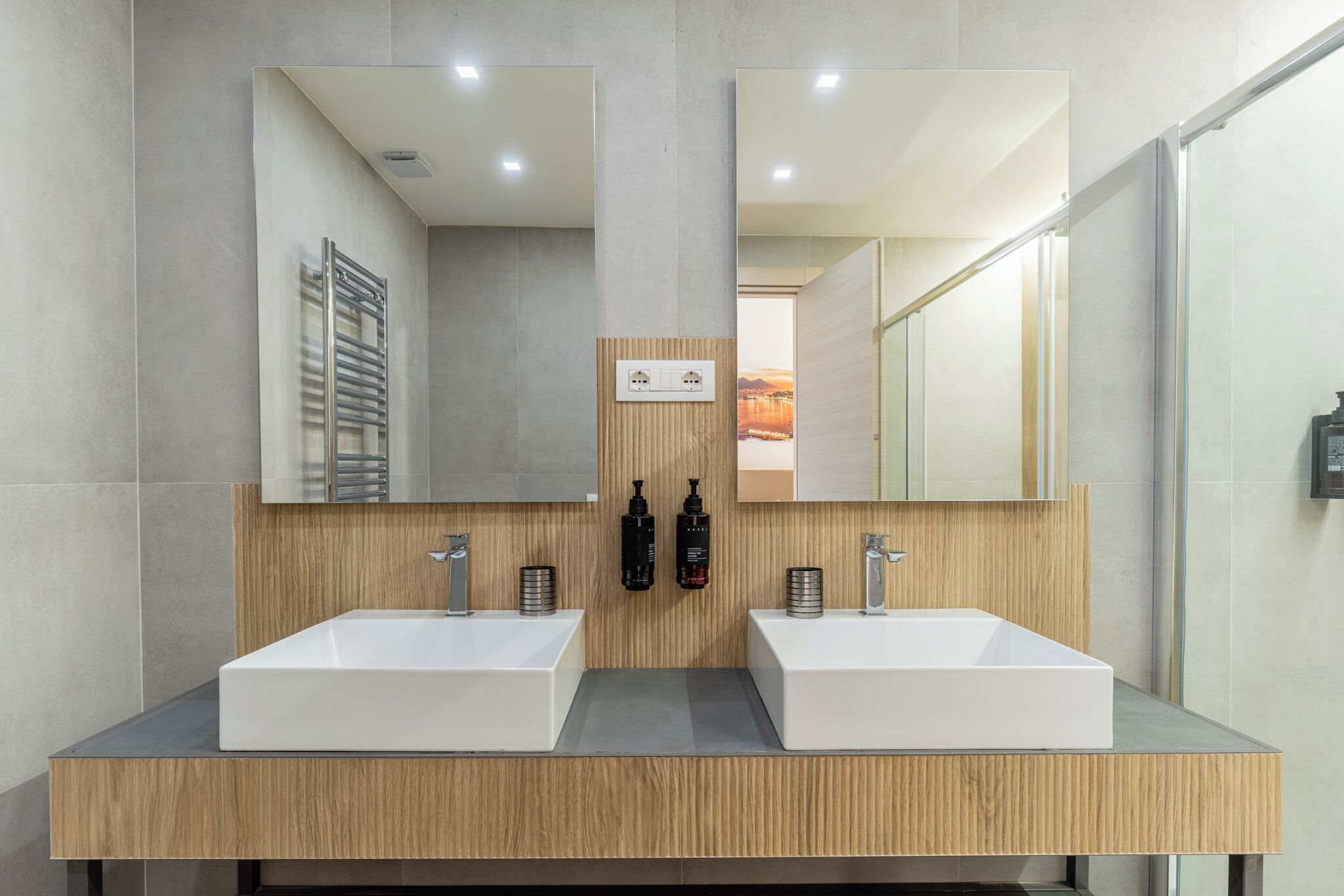 Ein modernes Badezimmer mit zwei Waschbecken, einem Spiegel und einer Holzausstattung.
