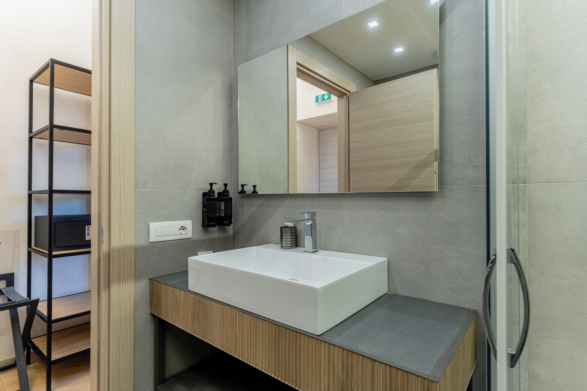 A modern bathroom with a white sink, a mirror, and a shower area.
