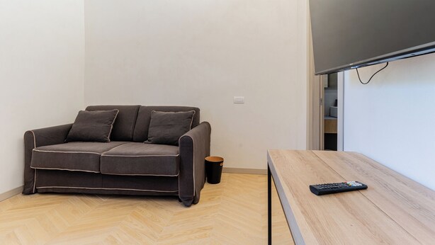 A small living area with a sofa, a table, and a TV. - Urban Vatican Rooms Cities of Art (Roma)