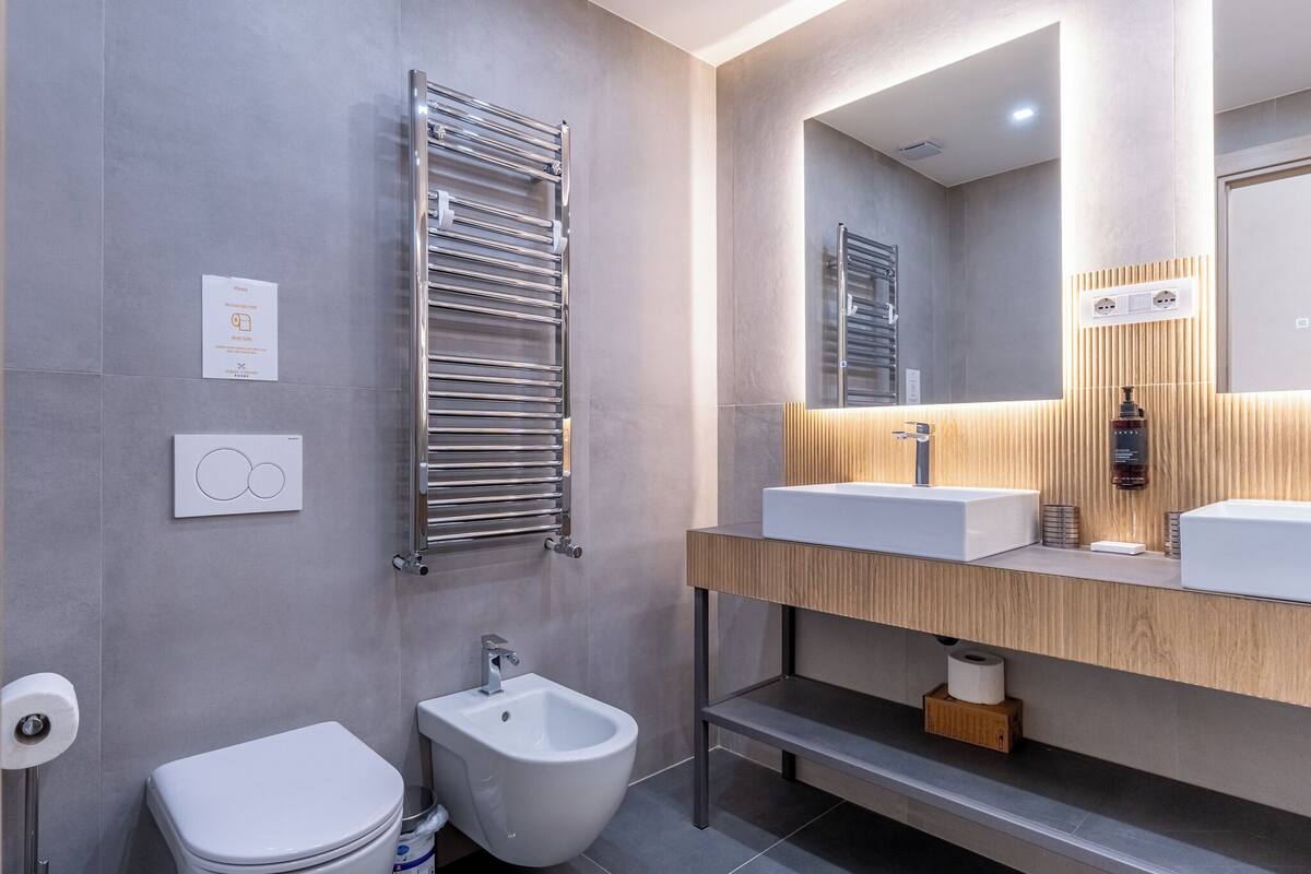 Un baño moderno con un bidé, un perchero, un espejo y un lavabo.
