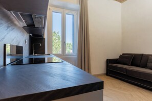 A modern kitchen with a built-in stove, a sink, and a window with curtains.