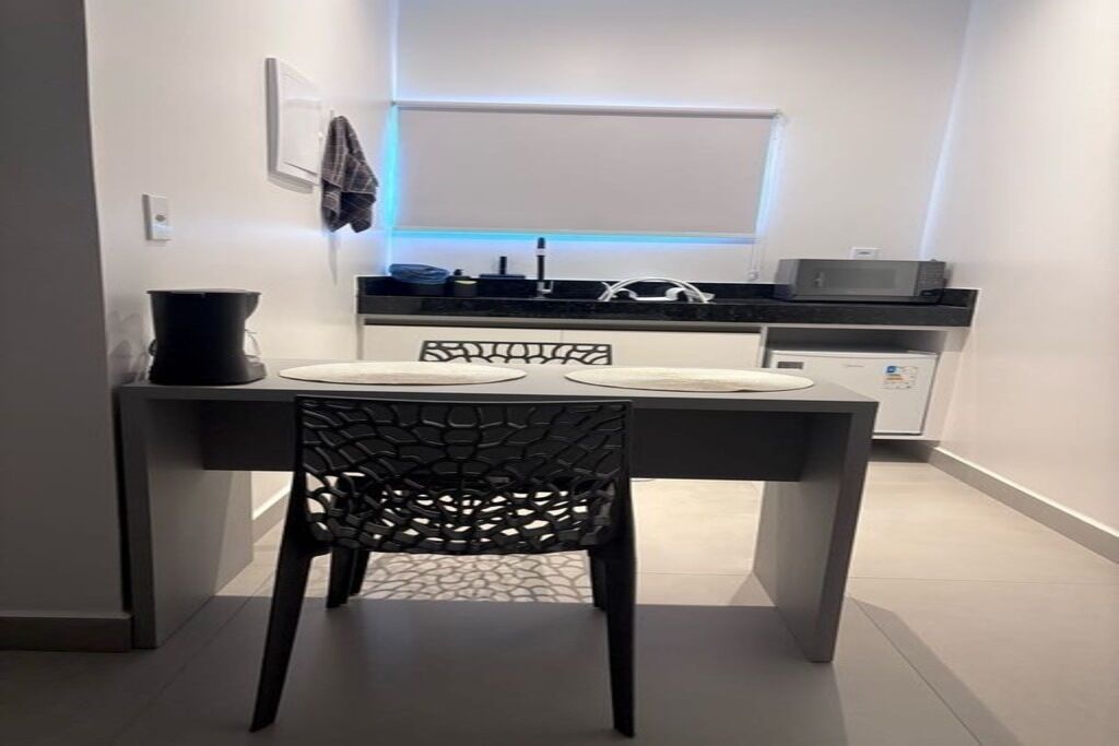 Uma cozinha moderna com área de refeições, incluindo uma mesa com cadeiras, micro-ondas e geladeira.