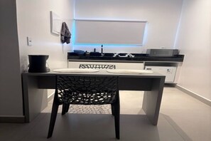 A modern kitchen with a dining area, including a table with chairs, a microwave, and a refrigerator. - Studio privativo em BG a 2km da praia (Cajueiro da Praia)