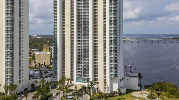 A high-rise hotel with multiple floors, a central courtyard, and a view of the water. - Dream Stay (Fort Myers)