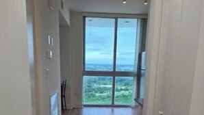 A hallway with wooden flooring leading to a large window with a view of greenery. - Dream Stay (Fort Myers)