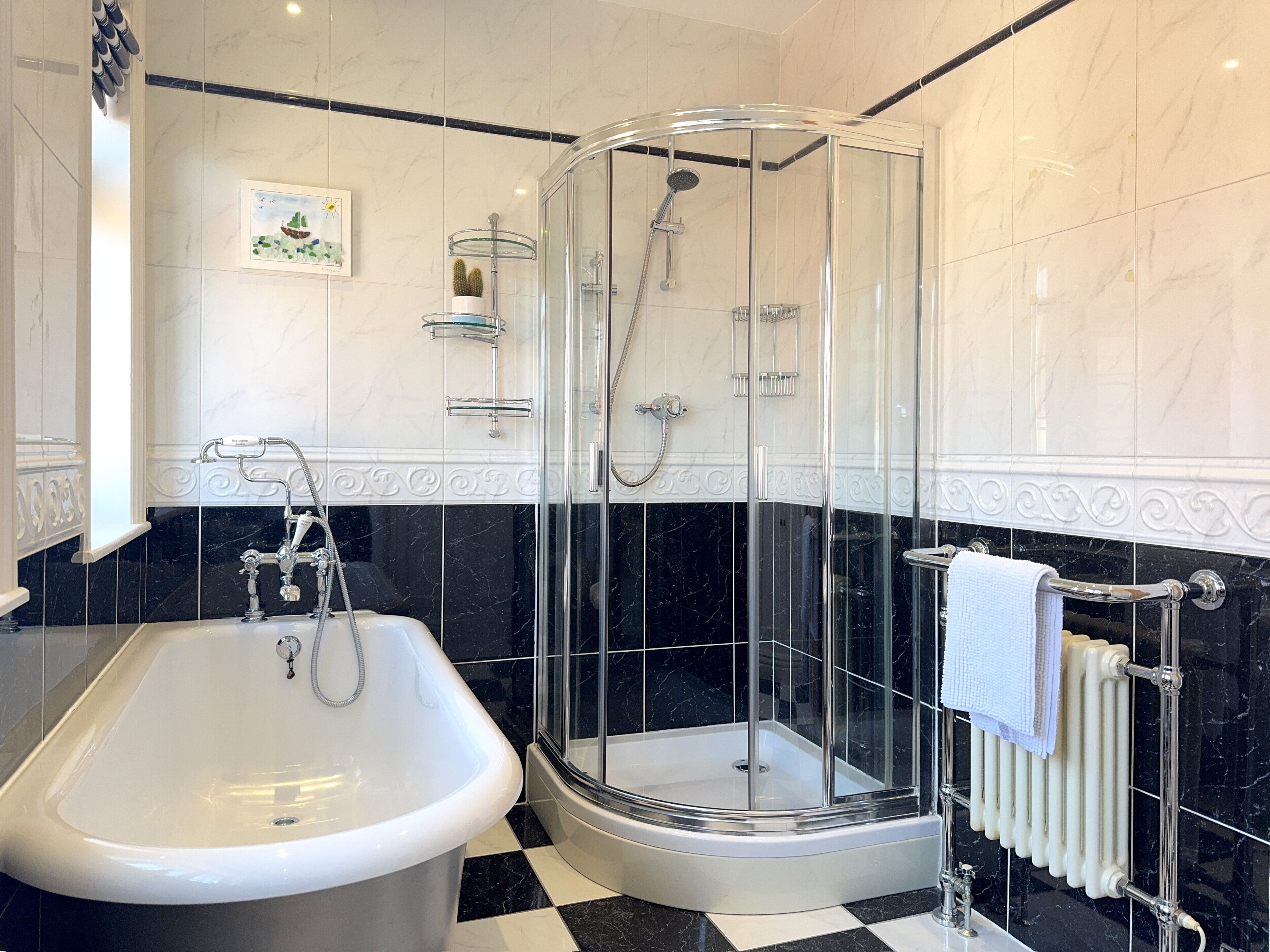 A bathroom with a bathtub, a glass-enclosed shower, and a white towel on a radiator.