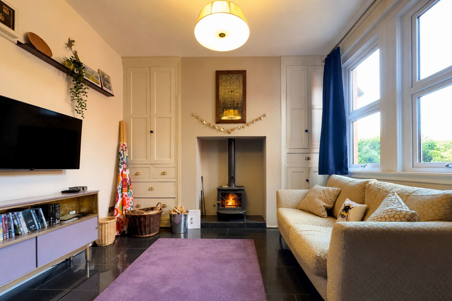 Una sala de estar con chimenea, un sofá, un televisor de pantalla plana y una estantería.