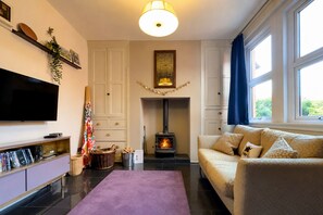 A living room with a fireplace, a sofa, a flat-screen TV, and a bookshelf.