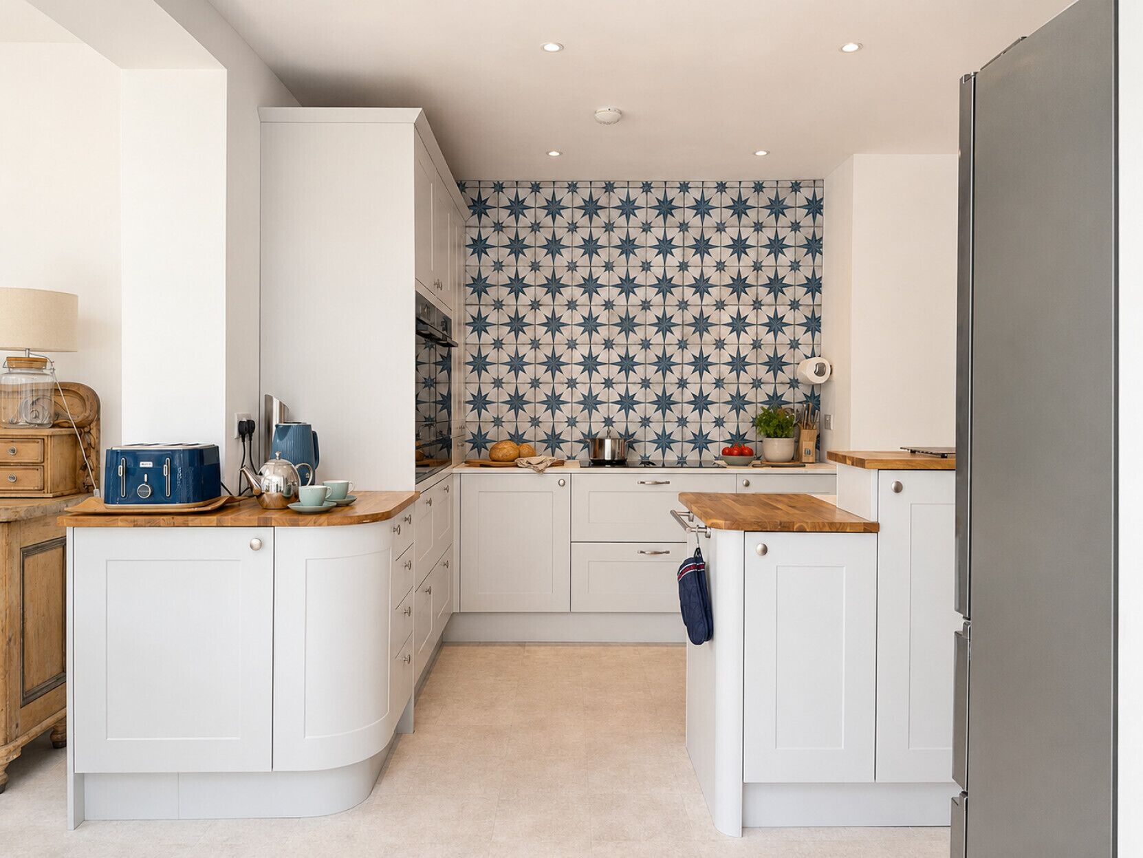 A kitchen with white cabinets, a wooden countertop, and a backsplash with a star pattern.