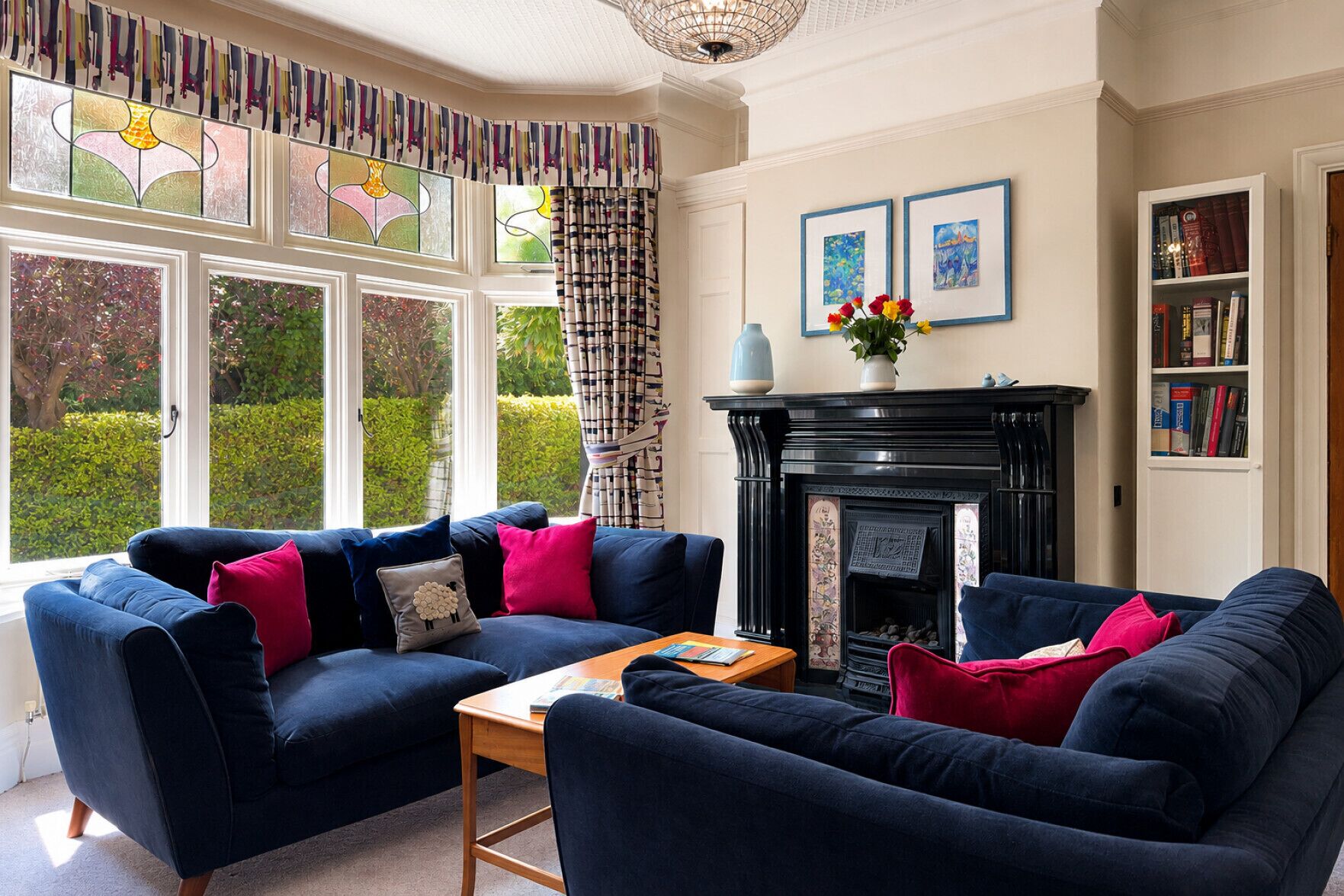 A living room with a blue sofa set, a fireplace, and a bookshelf.