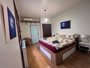 Ein Schlafzimmer mit Bett, Sessel, Kleiderschrank und Nachttisch.
