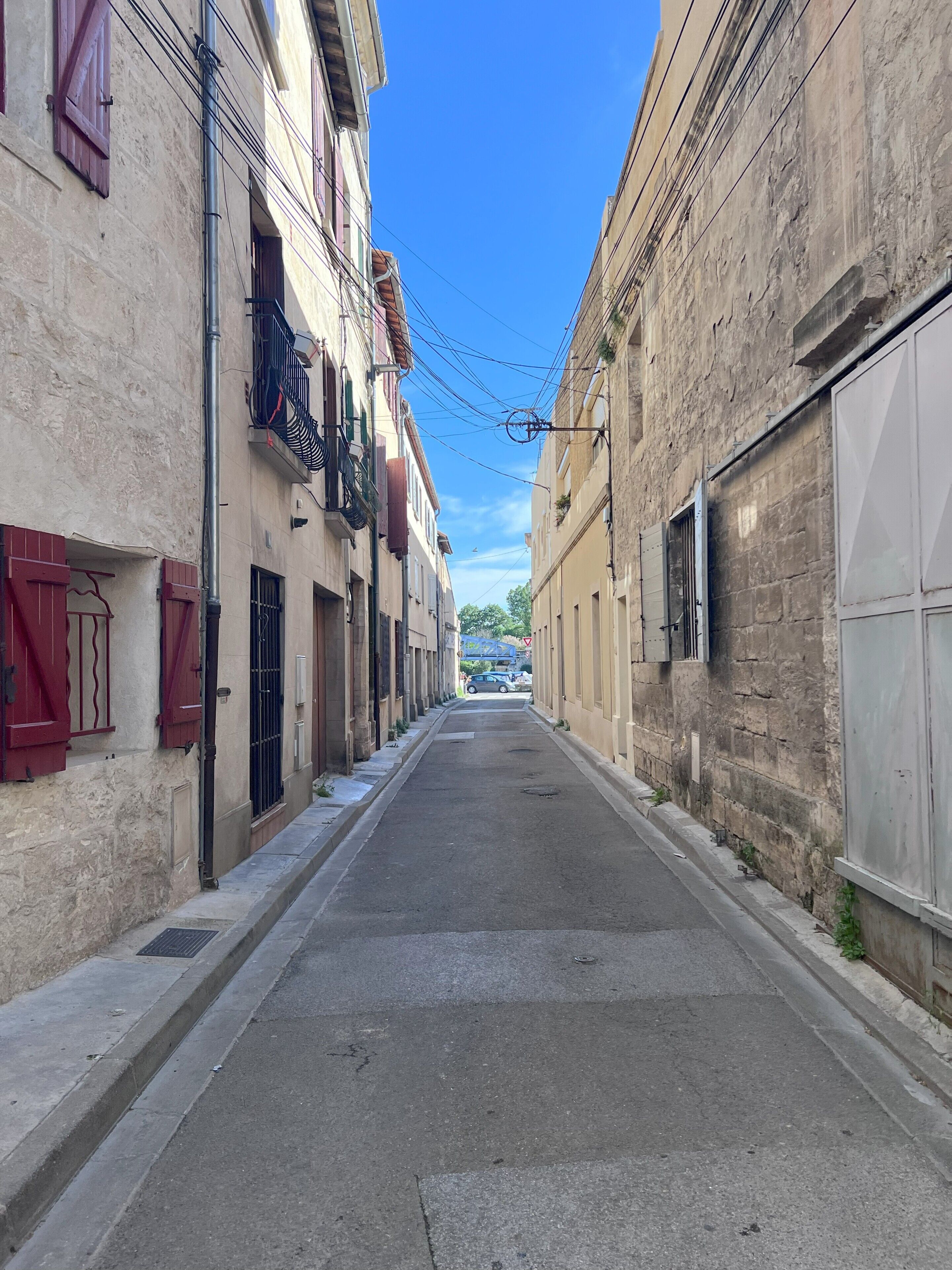 Une rue étroite bordée d’immeubles dotés de balcons et de volets.