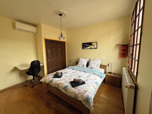 Ein Schlafzimmer mit einem Bett, einem Schreibtisch, einem Stuhl, einem Heizkörper und einem Fenster.