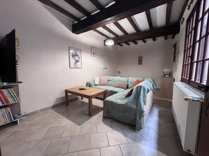 Ein gemütliches Wohnzimmer mit einem Ecksofa, einem Couchtisch aus Holz und einem Bücherregal.
