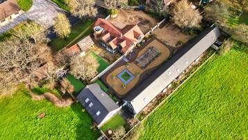 An aerial view of a residential property with a large house, a garden, and a long driveway.
