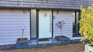 A house with a grey roof, a white door, and a small garden with two young trees. - Peaceful Dorset Cottage for 4 (Wimborne)