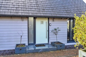 A house with a grey roof, a white door, and a small garden with two young trees. - Peaceful Dorset Cottage for 4 (Wimborne)