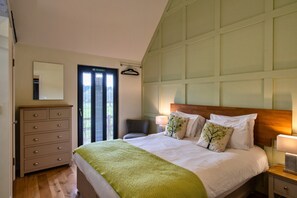 A bedroom with a bed, a dresser, a chair, and a window with blinds. - Peaceful Dorset Cottage for 4 (Wimborne)