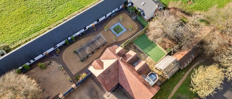 Vista aérea de una propiedad con un edificio alargado, un patio con césped verde y campos circundantes.