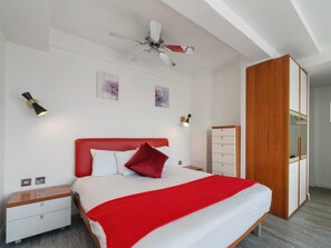 A bedroom with a bed, nightstands, a wardrobe, and a ceiling fan. - Smart Stay With Fitness Center (London)