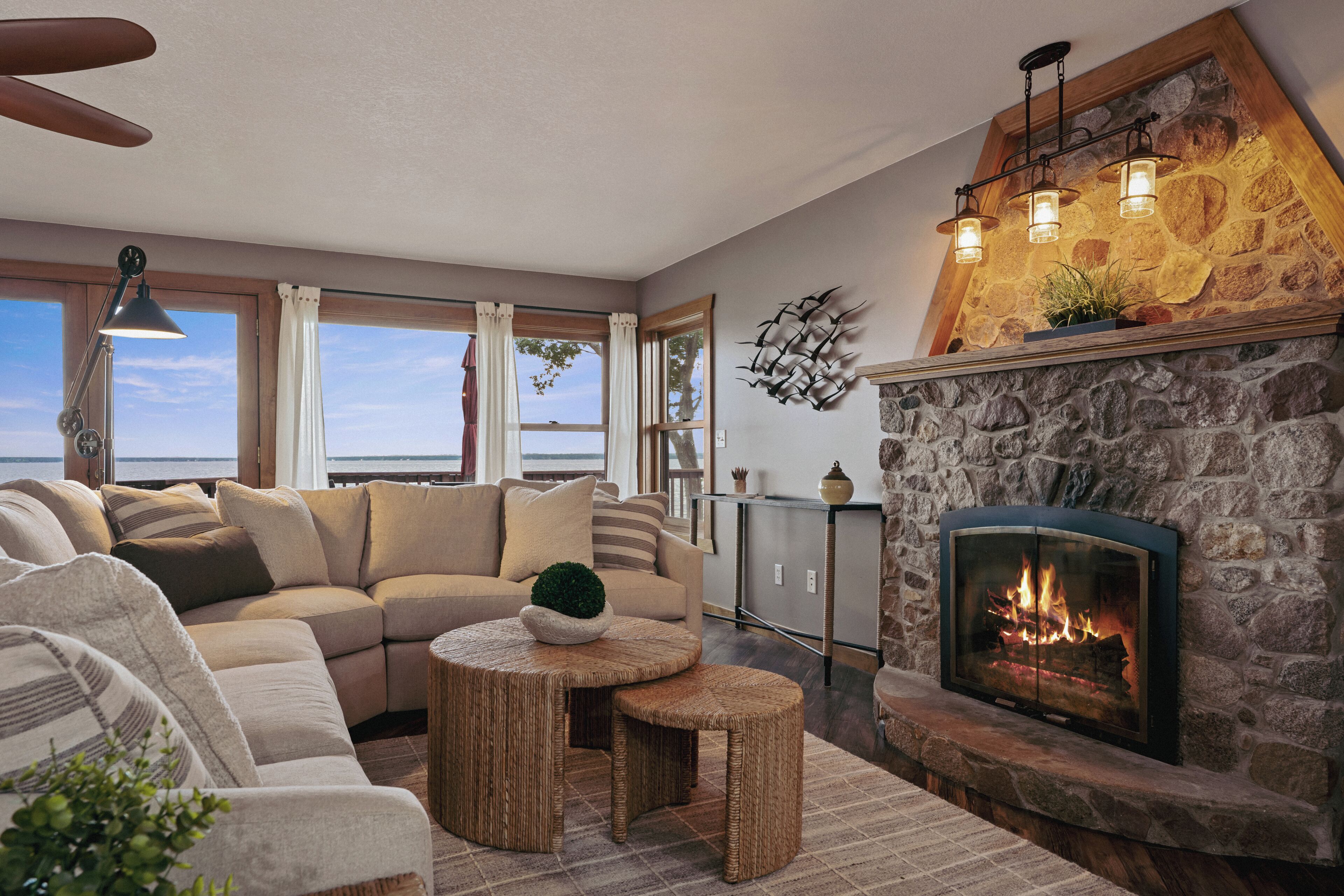 Un salón acogedor con chimenea de piedra, un ventanal con vistas al mar y un sofá cómodo.