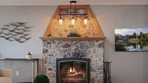 Ein Kamin aus Stein mit modernem Design, eine Deckenleuchte und ein gerahmtes Landschaftsbild an der Wand.