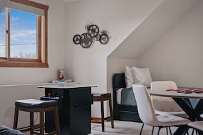 Una habitación acogedora con escritorio, silla y cama. Hay una ventana que proporciona luz natural y un adorno en la pared.