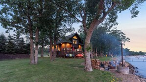 Eine Holzhütte mit einer Terrasse, umgeben von Bäumen, in der Nähe eines Gewässers.