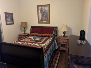 A bedroom with a bed, two bedside tables, a nightstand, a desk, and a chair.