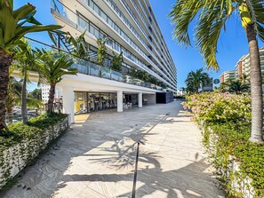 A modern hotel with a central courtyard, outdoor seating, and a Starbucks sign. - Luxury Corner Condo at Nima Bay | Marina Vallarta (Puerto Vallarta)