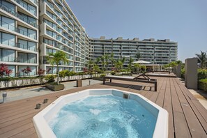Ein Hotel mit mehreren Etagen, einem Poolbereich auf dem Dach inklusive Whirlpool und umgebender Bepflanzung.