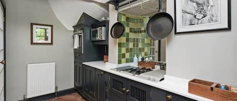 A kitchen with dark cabinetry, a white countertop, and a green-tiled backsplash.