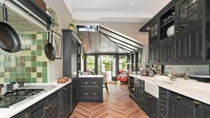 A modern kitchen with dark cabinetry, a herringbone floor, and a large island with a sink.