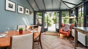 A conservatory with a dining table, chairs, and a red armchair.