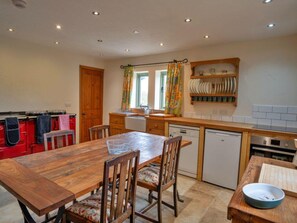 Eine kleine Küche mit Holztisch, Stühlen und einem eingebauten Geschirrspüler.