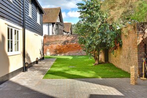 A courtyard with a paved walkway, a grassy area, a brick wall, and a tree. - Scenic Perthshire Chalet With Sauna (Maldon)