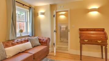 A room with a brown leather sofa, a wooden chest of drawers, and a window with curtains.
