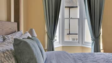 A bedroom with a bed, curtains, and a window.
