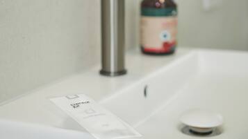 A bathroom sink with a paper towel dispenser and a bottle of hand soap.