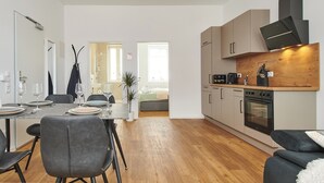 A modern kitchen with a built-in oven and a dining area with a table set for two. - HomeME Bad Oeynhausen City (Bad Oeynhausen)
