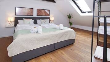 Une chambre moderne avec un grand lit, deux lampes fixées au mur, une lucarne et un plancher en bois.