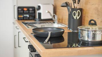 A kitchen with a stove, a frying pan, a pot, and a toaster.