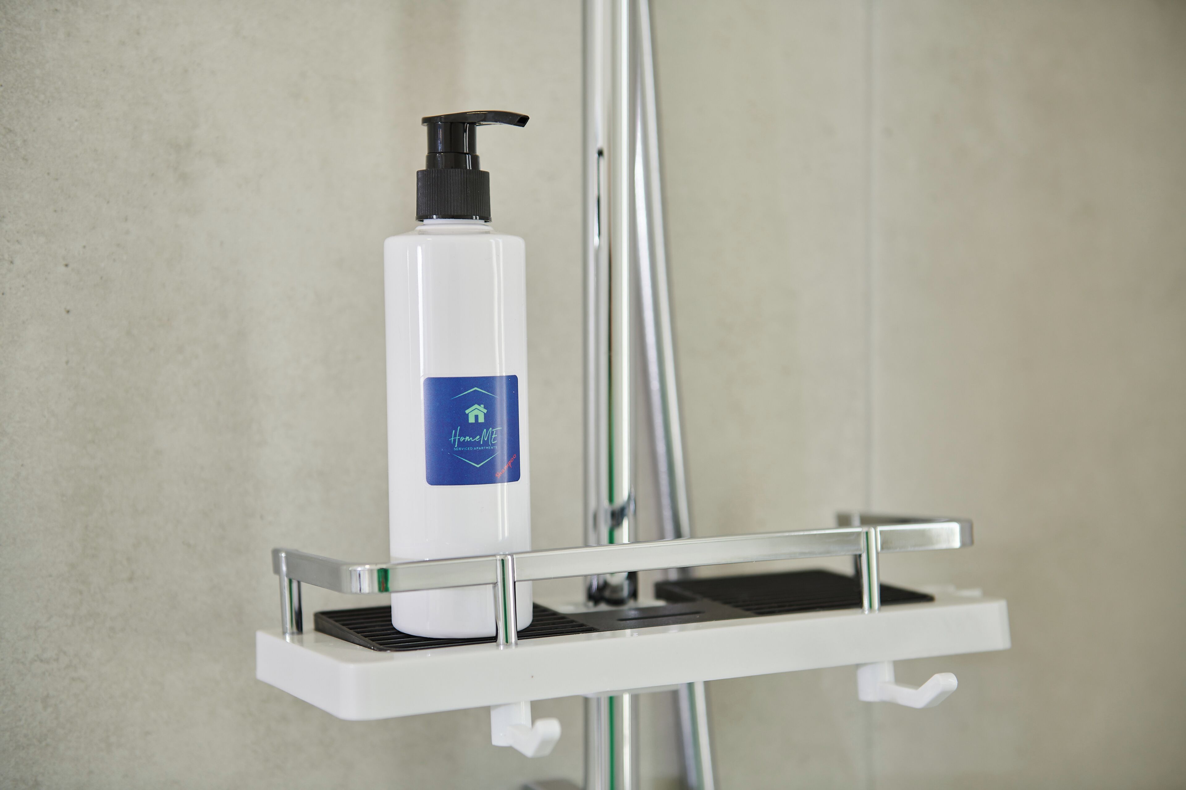 Une salle de bain avec un distributeur de savon blanc fixé sur un support chromé.