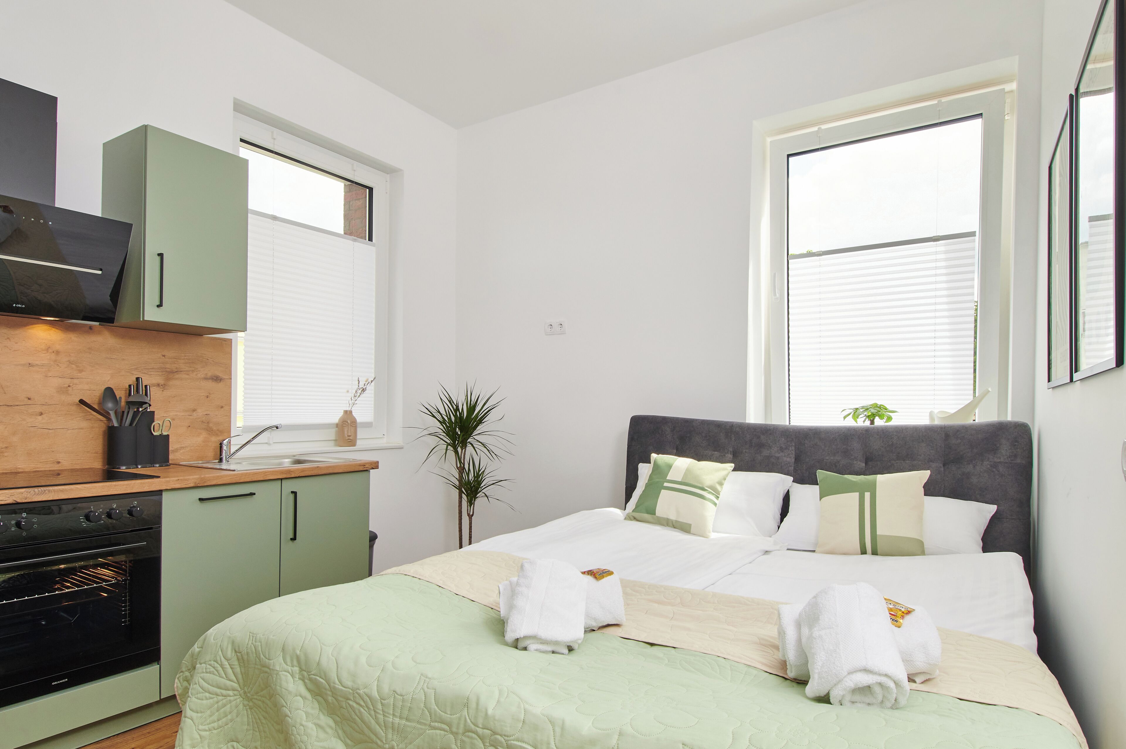 Une chambre moderne avec un lit, un four encastré, une fenêtre et une vue sur l’extérieur.