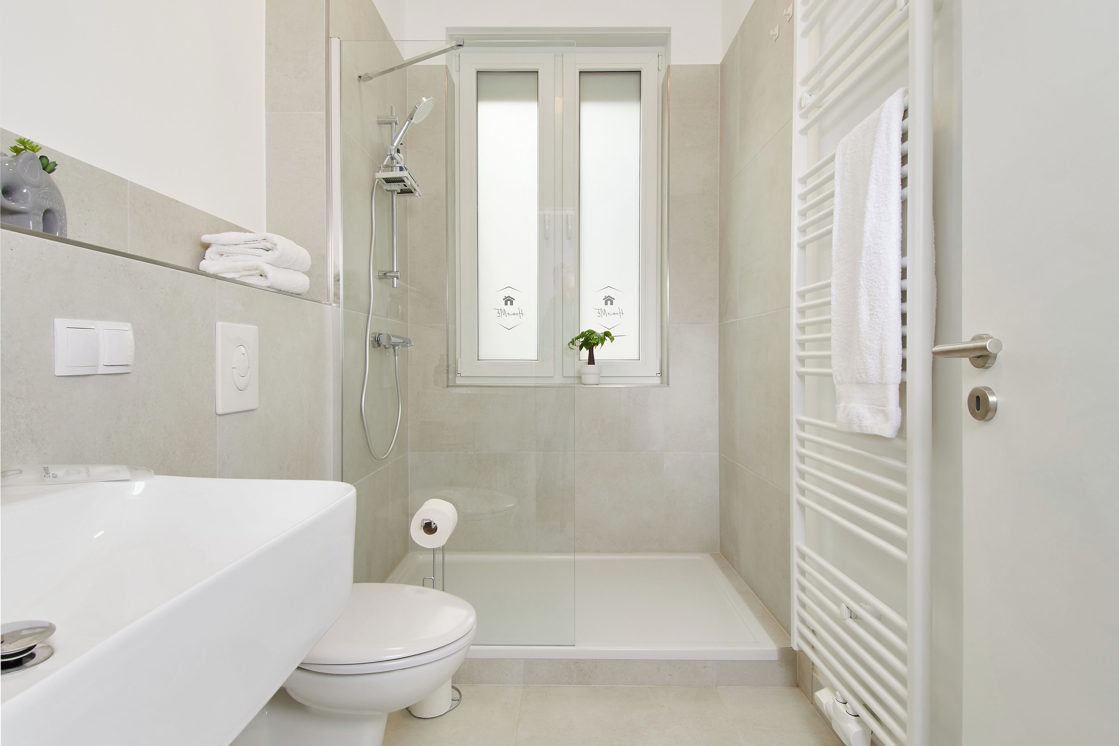 A modern bathroom with a shower, toilet, and a sink.