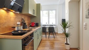 A modern kitchen with a wooden countertop, built-in oven, and a dining area with a table and chairs. - HomeME Bad Oeynhausen City (Bad Oeynhausen)