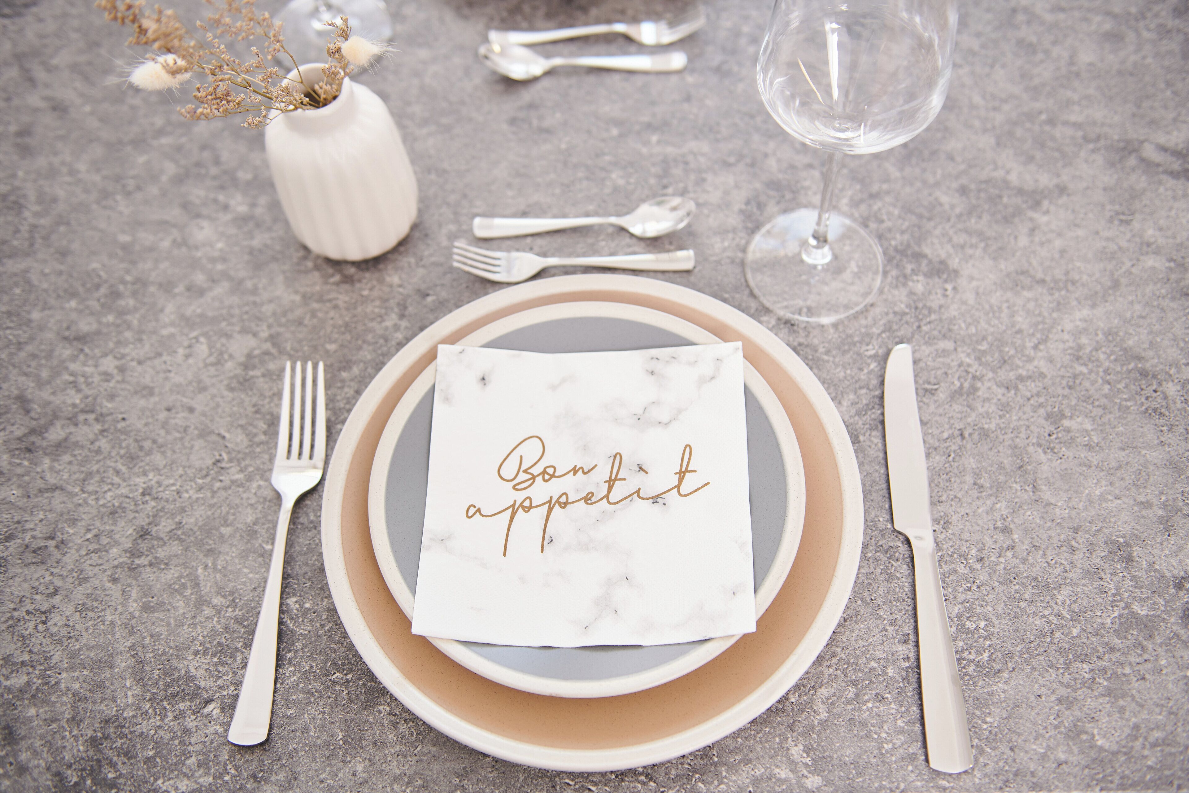 A table set with a plate, napkin, cutlery, and a glass of water.