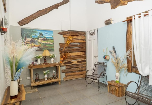 A rustic room with a wooden wall, a painting, a table with decorative items, and a chair.